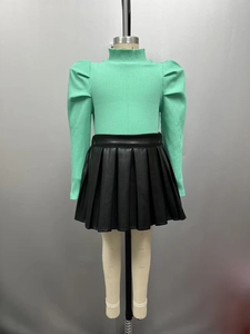 Détail du haut à manches longues vert menthe et jupe plissée en PU noir pour fille
