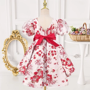 Détail d'une robe de princesse fleurie avec manches bouffantes et grand nœud rouge au dos