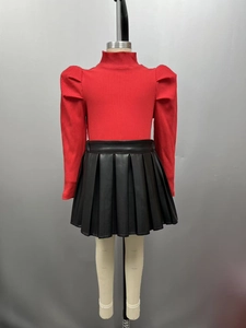 Détail du haut en maille côtelée rouge à manches bouffantes et jupe plissée en PU noir