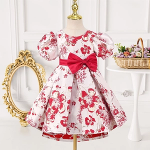 Détail de robe de princesse fleurie rose avec manches bouffantes et nœud satiné rouge