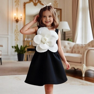 Dettaglio di un elegante abito nero senza maniche da bambina con grande camelia 3D bianca