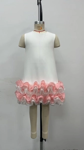 Detail of white sleeveless dress showing layered pink and white ruffled hem on mannequin