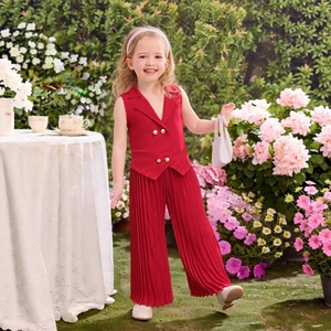 Detail of red sleeveless waistcoat and pleated wide-leg trousers for girls in a garden