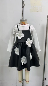 Détail d'un haut blanc côtelé et d'une robe en cuir avec appliqués floraux en 3D pour fille