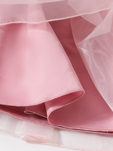 Detailed macro view of pink satin fabric layered with translucent tulle on a girl's dress