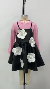 Détail du haut rose à manches longues et jupe en cuir noir avec grandes fleurs 3D blanches