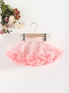 Pink multi-layer tutu skirt for girls with ruffled mesh hem hanging on a wooden hanger