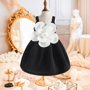 Dettaglio dell'abito nero senza maniche da bambina con grande fiore di camelia bianco