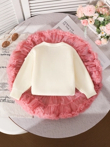 Girls cream knit sweater and pink tutu skirt two-piece set on marble background