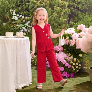 Detail of red sleeveless V-neck top with silver buttons and matching trousers on a girl