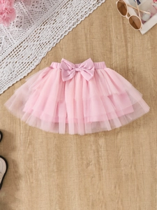 Detail of pink tulle tutu skirt with bow decoration and elastic waist on wood background