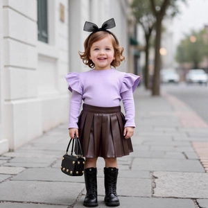 Detail of girls' purple ruffle knit top paired with a pleated leather skirt
