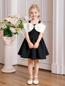 Elegant girls' A-line dress in black and white with a large bow and gold bead accents