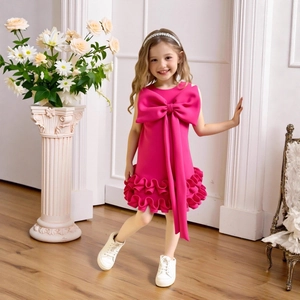 Detail of rose pink girls party dress featuring large bow and layered ruffle hemline
