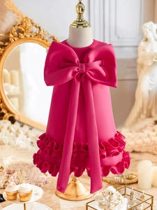 Detail of rose pink dress featuring a large bow and layered ruffled hem for girls