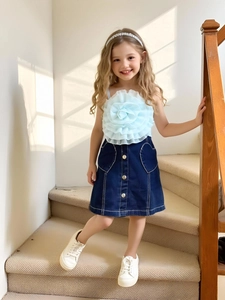 Ensemble fille avec haut à fleurs et jupe en jean avec poches cœur sur l'escalier