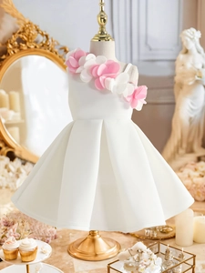 Detail of white sleeveless flower girl dress with pink petals and pleated skirt