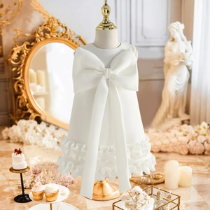 Detail of white princess dress featuring large bow ornament and tiered ruffle skirt