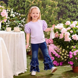 Close-up of girls' purple puff sleeve top and flared denim pants with pearl details