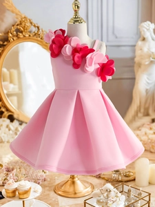 Close-up of pink girls party dress featuring 3D floral accents on shoulder and pleated skirt