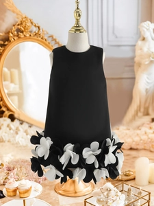 Detail of a sleeveless black girls gown featuring 3D floral petals on the hemline