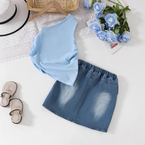 Dettaglio del set estivo da bambina con top monospalla azzurro e gonna in denim con accessori