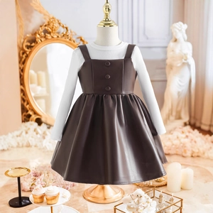 Détail de la robe chasuble en cuir PU marron et pull en maille côtelée blanche