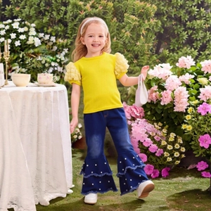Detail of yellow puff sleeve top and flared jeans with pearls for toddler girls