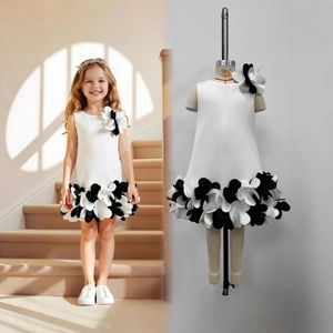Détail d'une robe blanche sans manches avec fleurs 3D noires et jupon à volants
