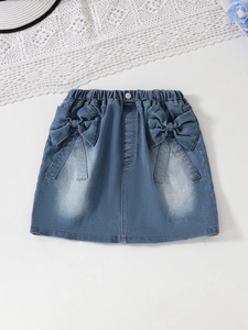 Gonna di jeans per bambine con elastico in vita e fiocchi 3D, posata su sfondo bianco