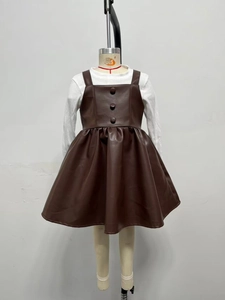 Détail d'une robe chasuble en similicuir marron pour fille avec trois boutons décoratifs