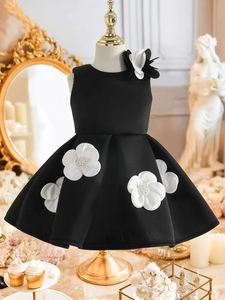 Détail d'une robe élégante en satin noir pour fille avec grandes appliques florales 3D