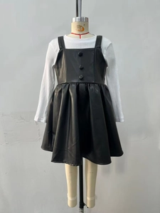 Détail d'une robe chasuble pour fille en similicuir noir avec boutons décoratifs