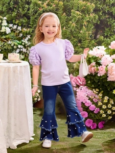 Girls summer set with purple puffed sleeve top and pearl flared jeans on garden background