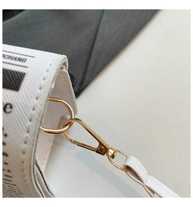 Close-up of newspaper print bag with golden metal spring hook and matching strap