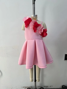 Detail of pink girls' dress with 3D floral accents on single shoulder and pleated skirt
