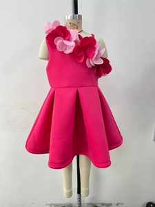 Detail of rose pink dress featuring handmade 3D floral accents and pleated A-line skirt