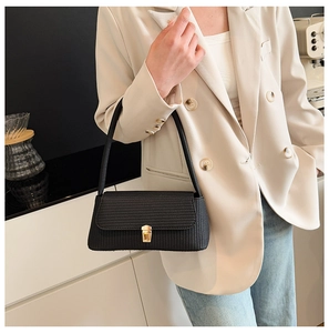 Detail of black woven shoulder bag featuring a gold square buckle and minimalist design