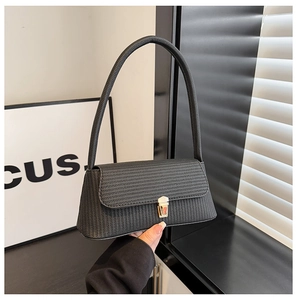 Close-up of black woven shoulder bag featuring a sleek gold buckle and slim straps