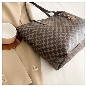 Detail der bedruckten Monogramm-Tote-Bag mit Ledergriff und Metall-M-Anhänger