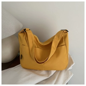 Close-up of bright yellow large tote bag with front pockets on striped fabric