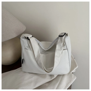 Detailed close-up of white tote bag on soft fabric with an adjustable shoulder strap