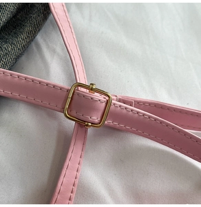 Detail of pink leather bag strap with a square golden metal buckle and stitching
