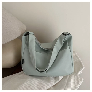 Detail of mint green nylon crescent bag showing smooth fabric texture and wide shoulder strap