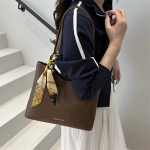Grand sac cabas marron avec foulard en soie porté par un mannequin dans un escalier