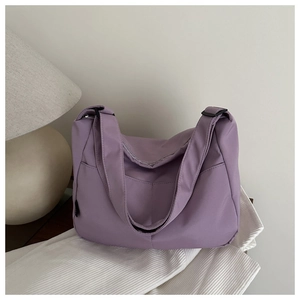 Detail view of large lavender tote bag with adjustable strap on white textured fabric