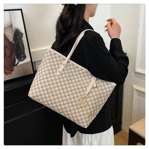 Detail der großen Shopper-Tasche mit M-Print und Metallanhänger getragen am Model