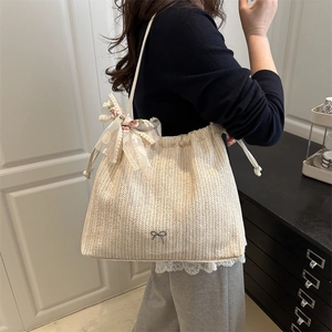 Beige woven tote bag with drawstring closure and floral lace bow for summer styling