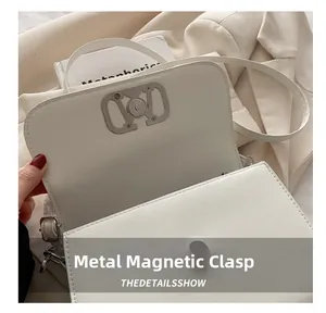 Détail du fermoir magnétique en métal doré sur le sac à main en cuir blanc chic