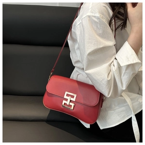 Détail du sac bandoulière rouge carré avec boucle dorée porté par un mannequin